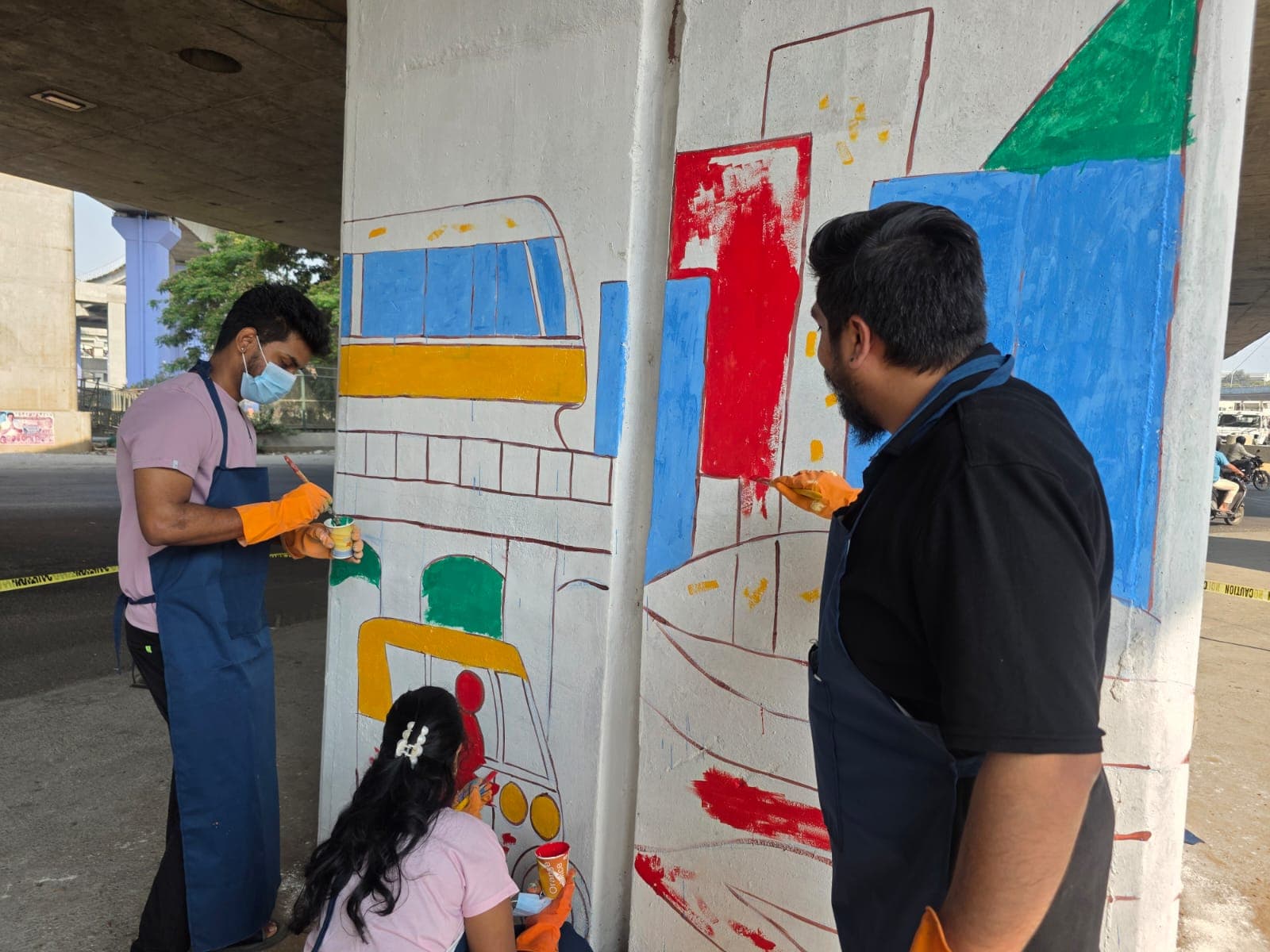 Volunteers adding colorful shapes to an underpass pillar