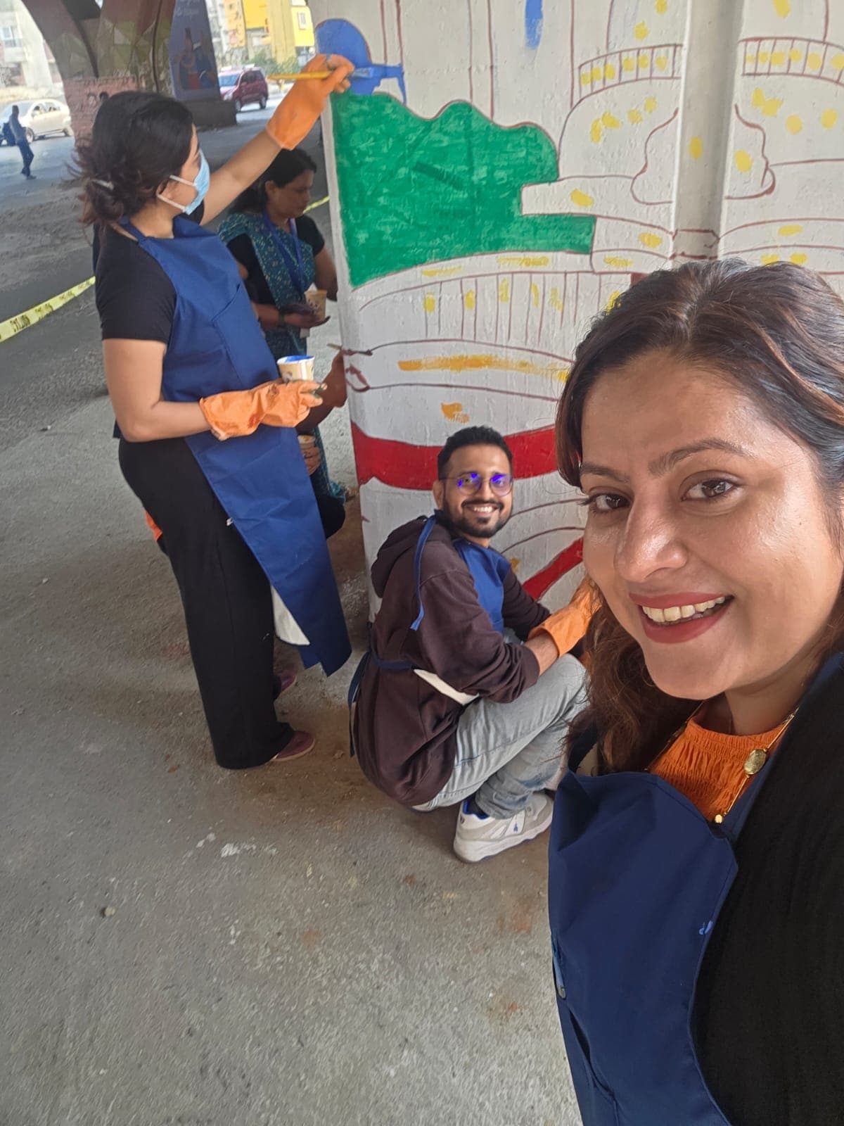 Volunteers painting a colorful mural on an underpass pillar